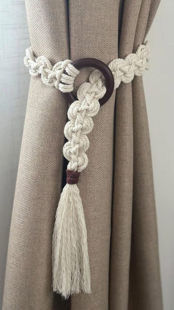 Elegant curtain tieback with a braided rope and tassel, enhancing brown fabric drapes with a modern touch.