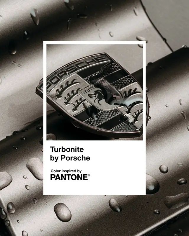 Porsche emblem with raindrops on dark turbonite color surface inspired by Pantone, showcasing elegance and design.