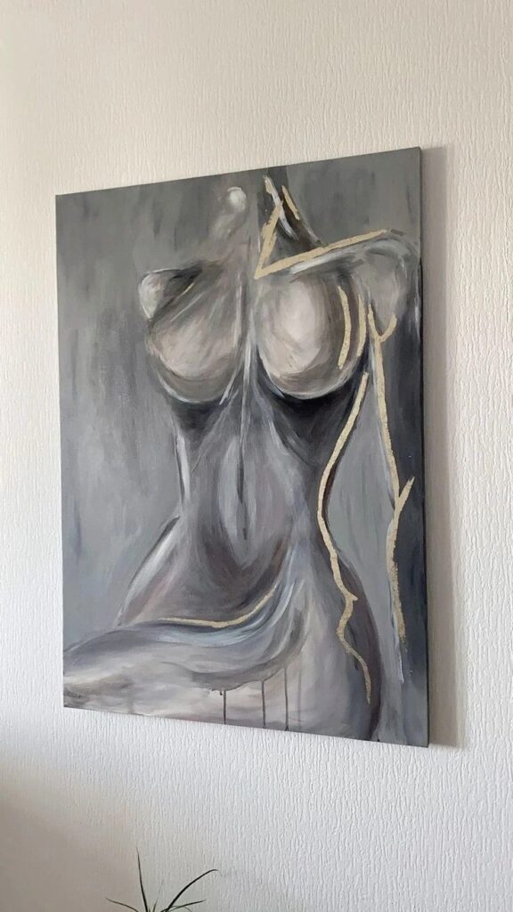 Abstract grayscale painting of a female torso with gold accents on a textured wall.