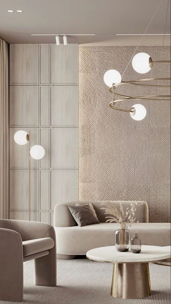 Modern living room with textured walls, elegant lighting, beige sofa, armchair, and decorative vases on a round table.