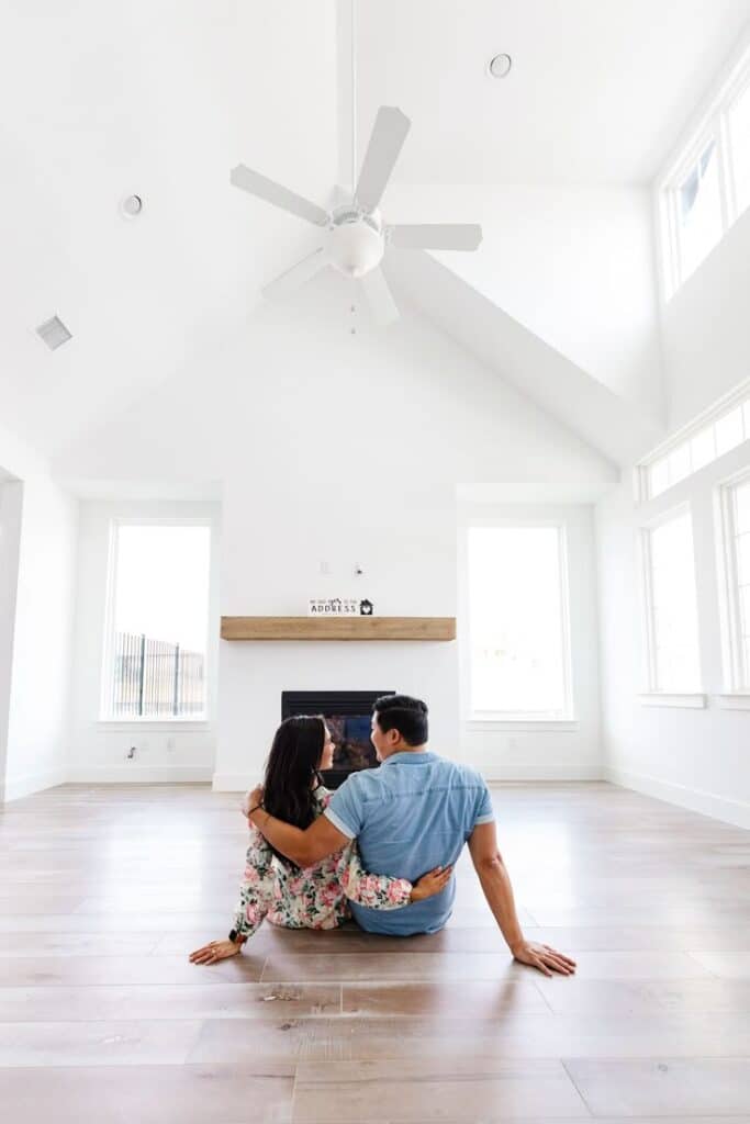 _ 16 Couple sitting on hardwood floor in bright, modern living room with vaulted ceiling and fireplace. | Sky Rye Design Couple sitting on hardwood floor in bright, modern living room with vaulted ceiling and fireplace.