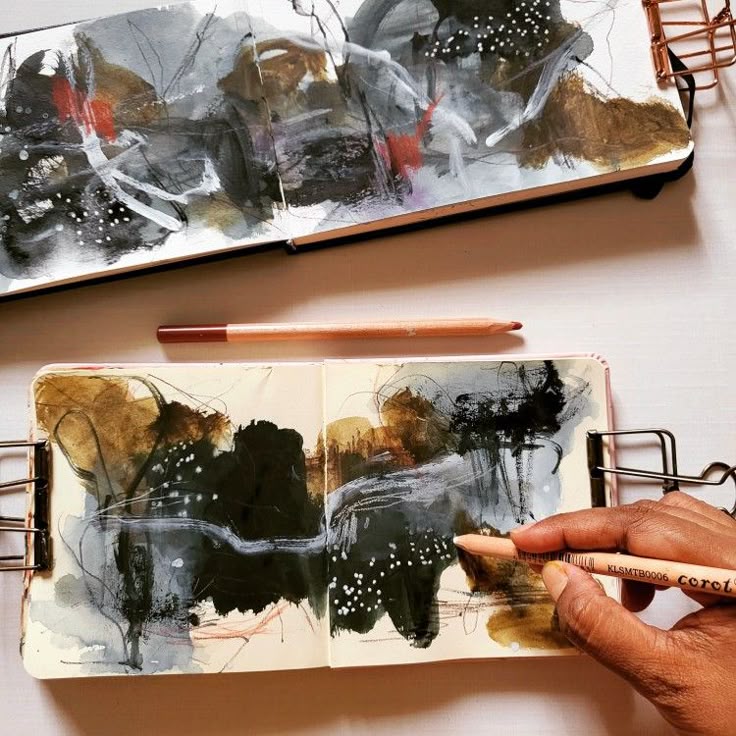Person sketching abstract art in a notebook with pastel crayons, exploring creativity and color.