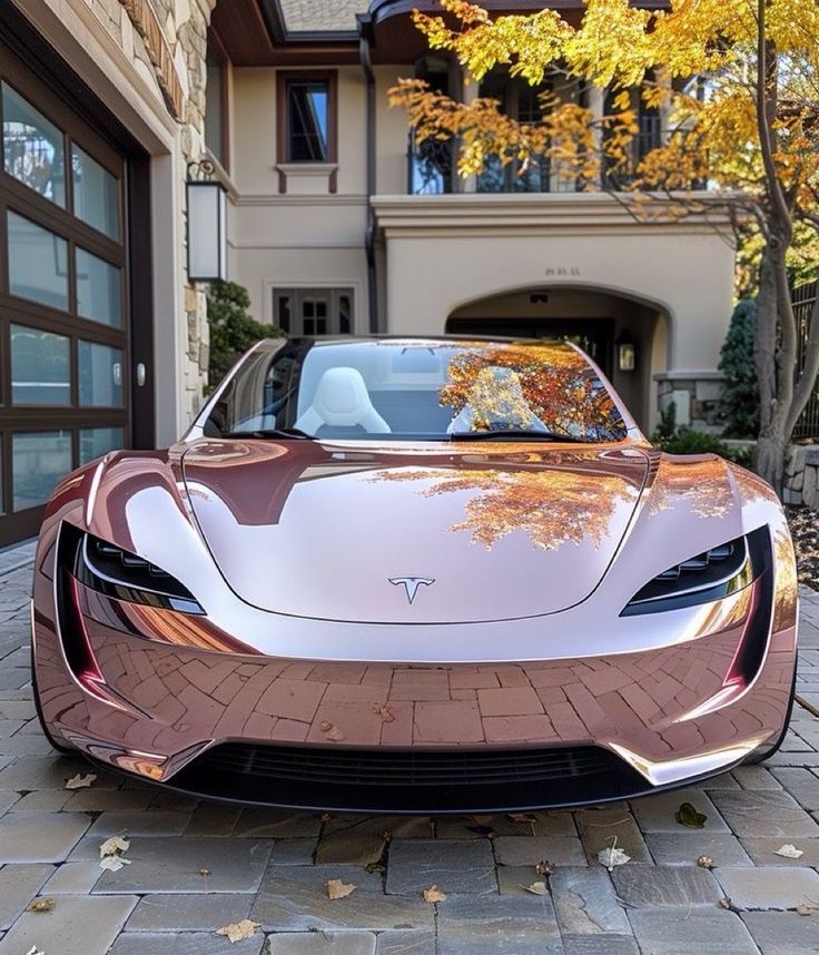 Sleek pink Tesla sports car parked in driveway, reflecting autumn leaves, in front of luxury home.