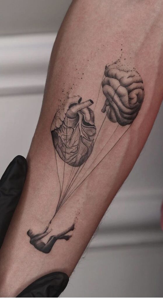 Tattoo of heart and brain connected by strings to a floating figure, symbolizing the mind-body connection.