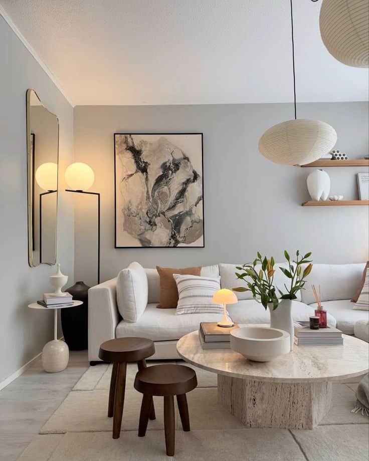 Modern living room with beige sofa, abstract wall art, and round coffee table topped with decor and plants.