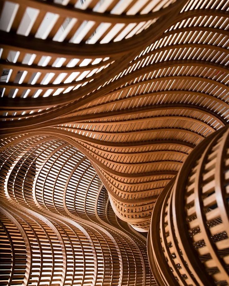 Abstract wooden structure with flowing, intertwined curves and slatted design, creating a dynamic architectural pattern.