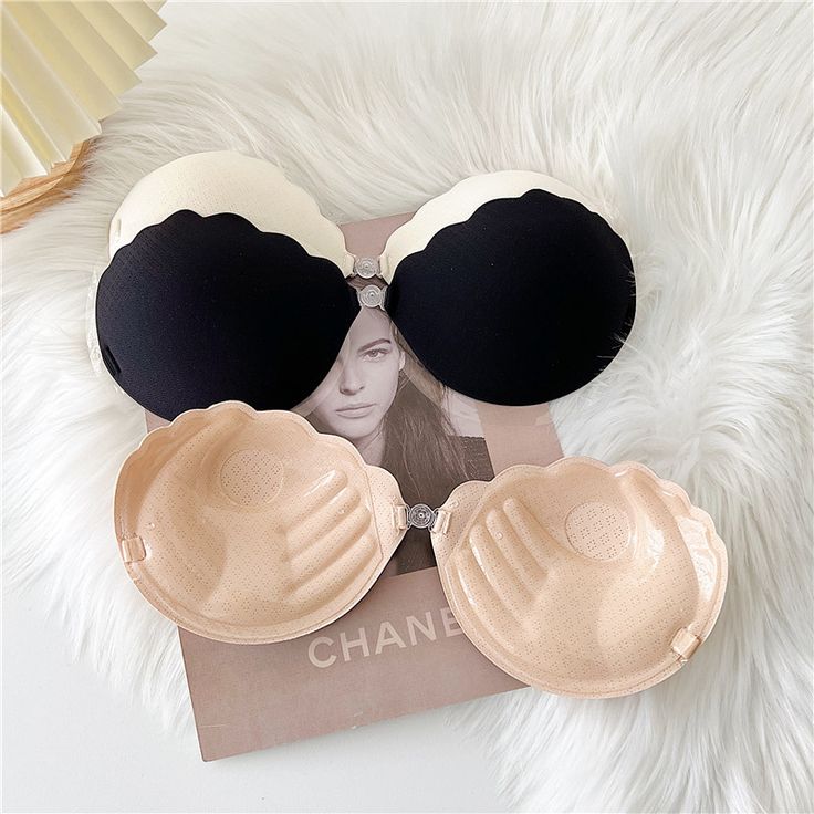 Black and beige strapless bras with scalloped edges laid on a white fur surface.
