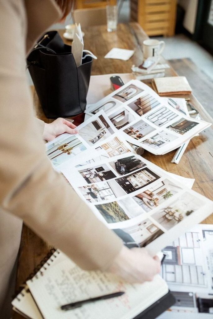 Person reviewing interior design layouts and notes at a table, planning decoration ideas.
