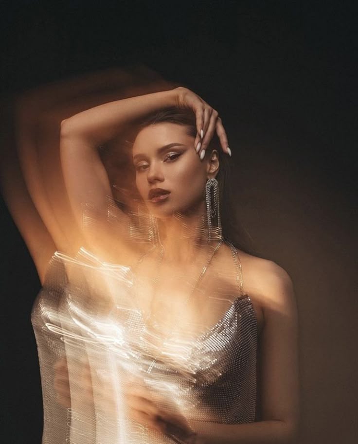 Glamorous woman in a silver dress with dynamic light effects, posing elegantly against a dark background.