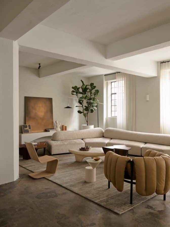 Modern living room with beige sectional sofa, minimalist decor, and large windows for natural light.