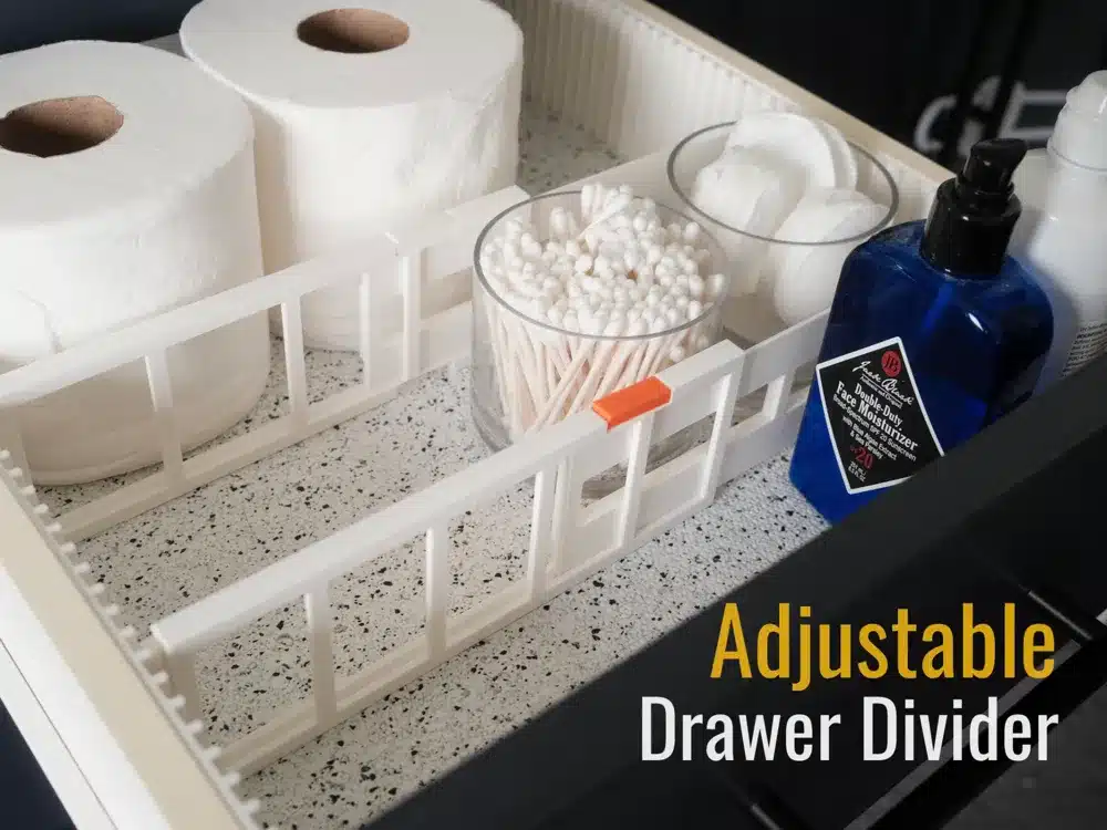 Adjustable drawer divider organizing toiletries and bathroom essentials in white tray on speckled surface.