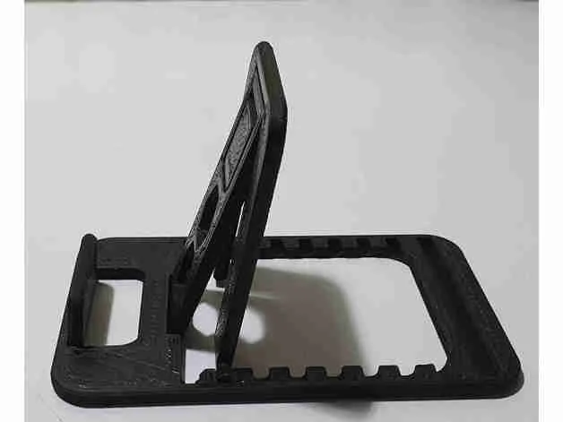 Adjustable black plastic stand on a white surface, used for holding devices at multiple angles.