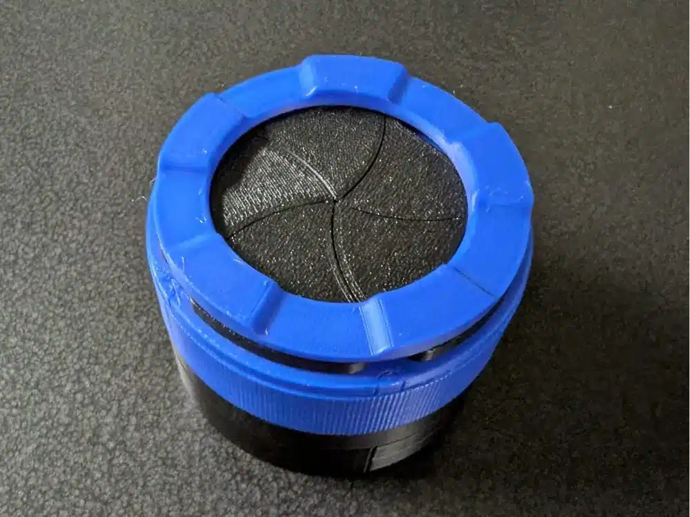 Blue and black 3D-printed container with a geometric pattern on a textured black surface.