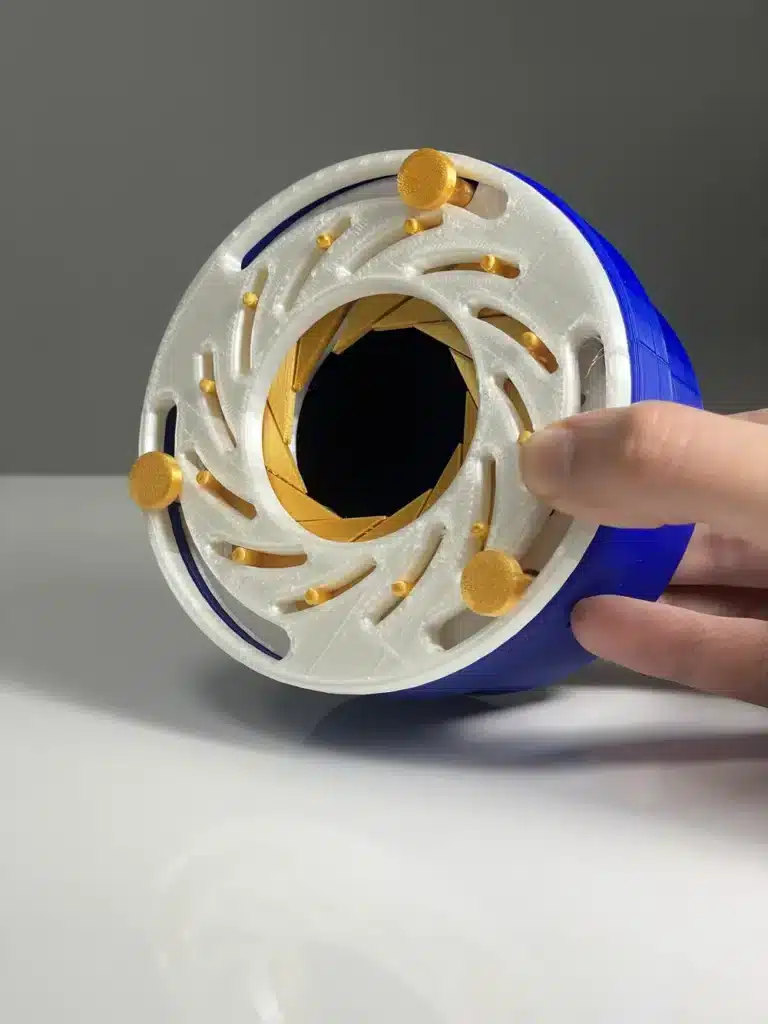 3D printed kinetic sculpture with intricate white and blue design, held by a hand on a reflective surface.