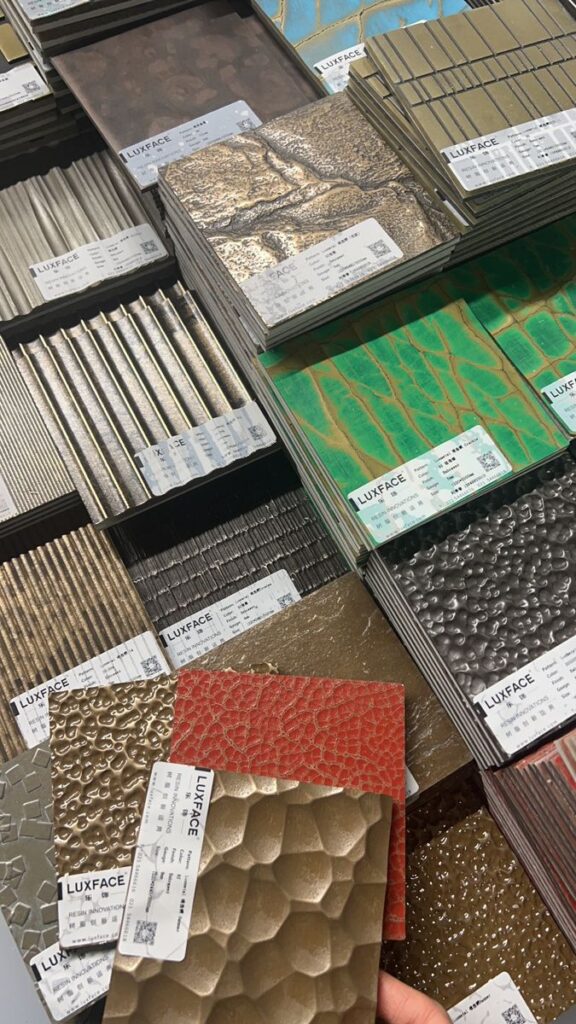Various decorative metal panels stacked with different textures and colors, labeled Luxface, showcasing design options.