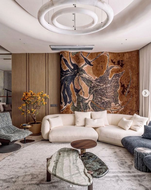 Elegant living room with abstract wall art, modern white sofa, unique coffee tables, and circular ceiling light.
