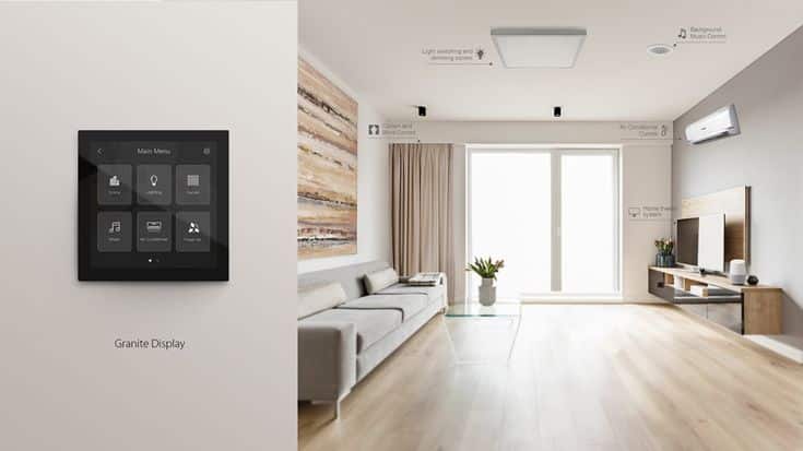 Modern living room with smart home controls, featuring a wall-mounted touch display, cozy sofa, and large window view.