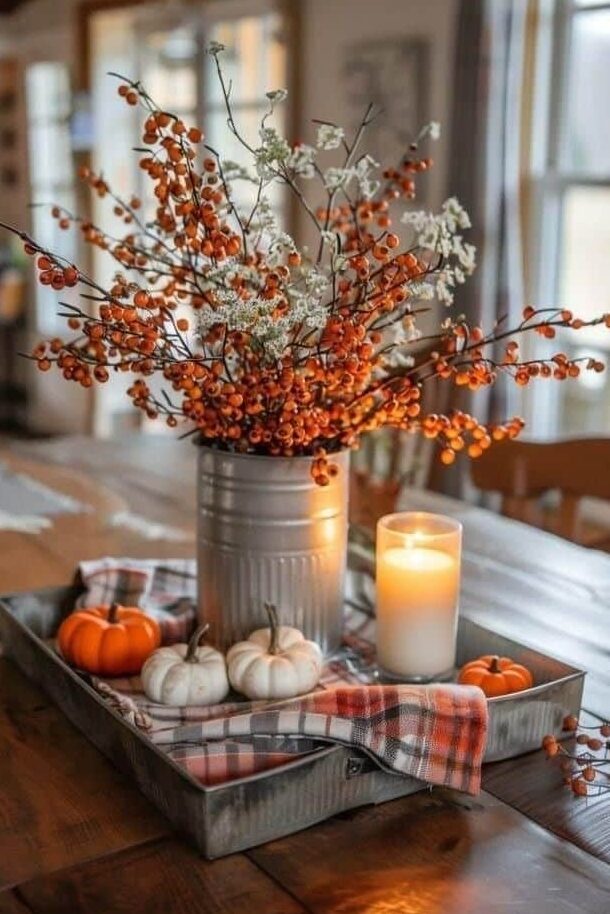 Rustic autumn table centerpiece with orange berries, small pumpkins, and candle on plaid cloth. Warm fall decor.
