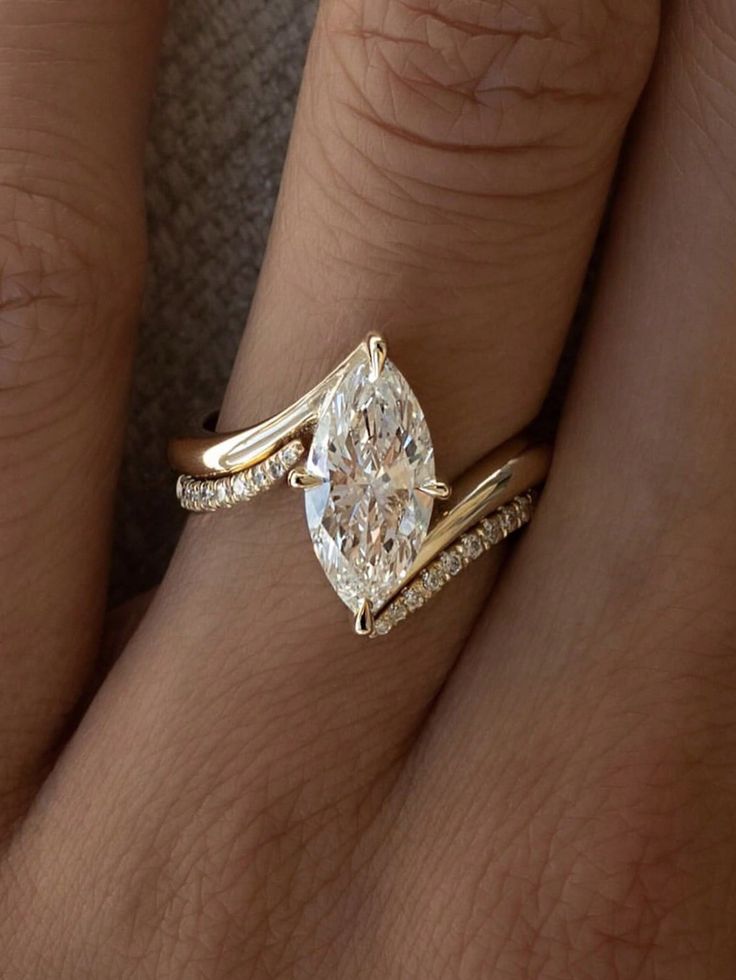 Gold ring with a marquise diamond and pave band on finger, elegant and sparkling design.
