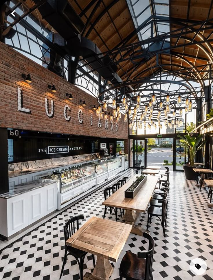 Modern ice cream shop interior with industrial design, wooden tables, and large windows for natural light.