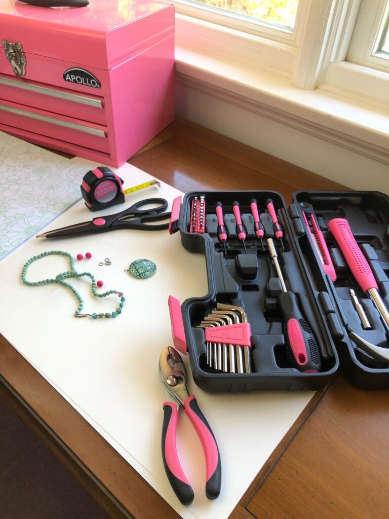 Pink tool set with case and toolbox for DIY crafts, featuring pliers, screwdrivers, and a measuring tape.