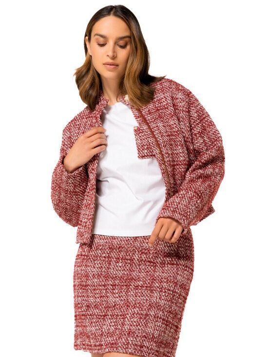 Woman in red tweed jacket and skirt set, posing confidently on a white background. Fashionable ensemble.