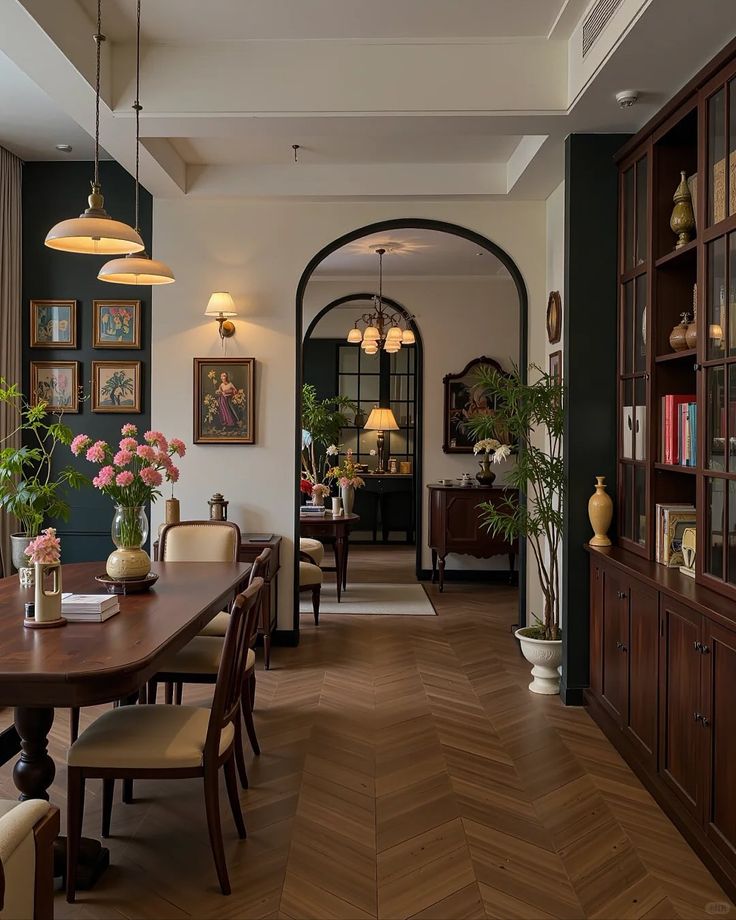Elegant dining room with wooden furniture, arched doorway, floral decor, and cozy lighting for a warm atmosphere.
