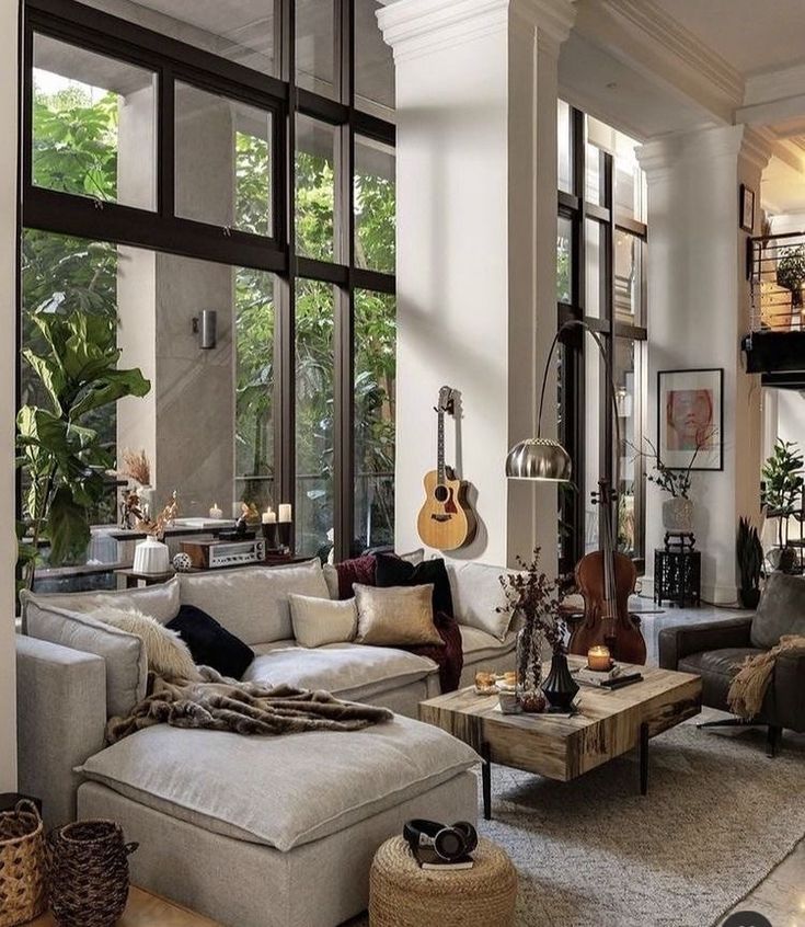 Modern living room with large windows, cozy sectional sofa, guitar, and cello, blending natural and elegant decor.