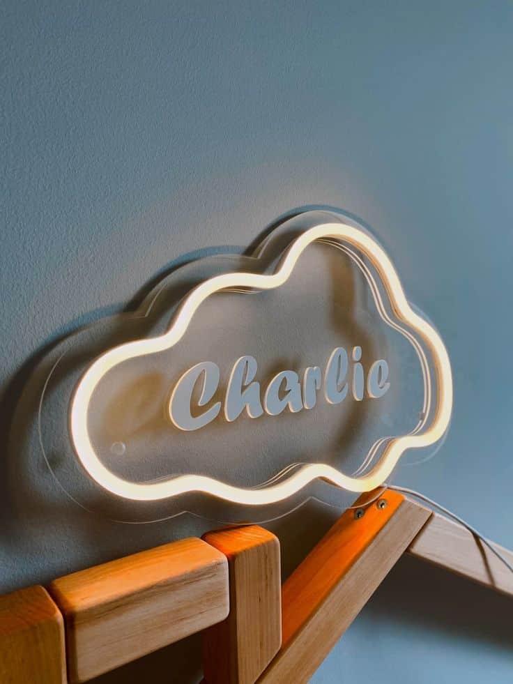 Glowing cloud-shaped neon sign reading Charlie on a blue wall, with wooden accents below.