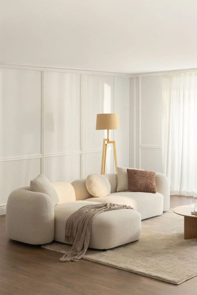 Modern living room with beige sofa, floor lamp, and soft lighting. Cozy interior design with neutral tones.