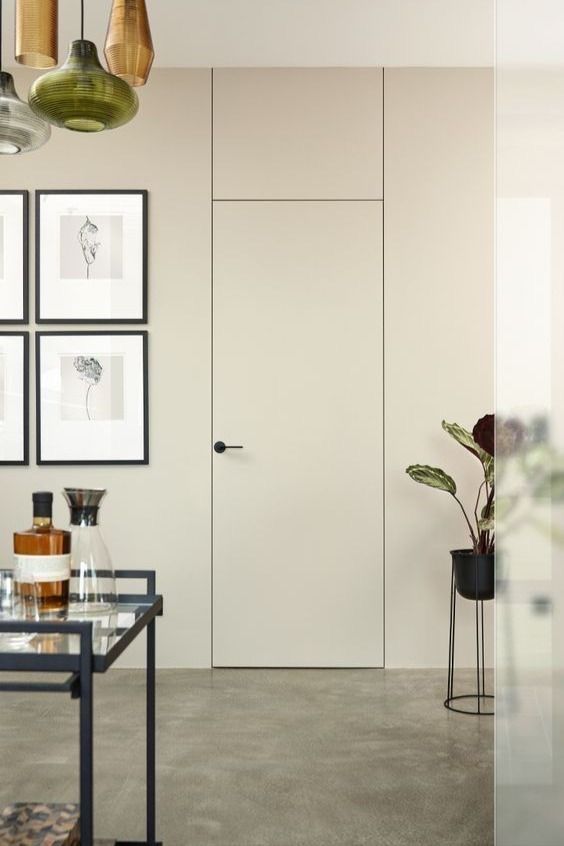 _ 4 Modern minimalist room with wall art, hidden door, and decor accents, including glassware and a potted plant. | Sky Rye Design Modern minimalist room with wall art, hidden door, and decor accents, including glassware and a potted plant.