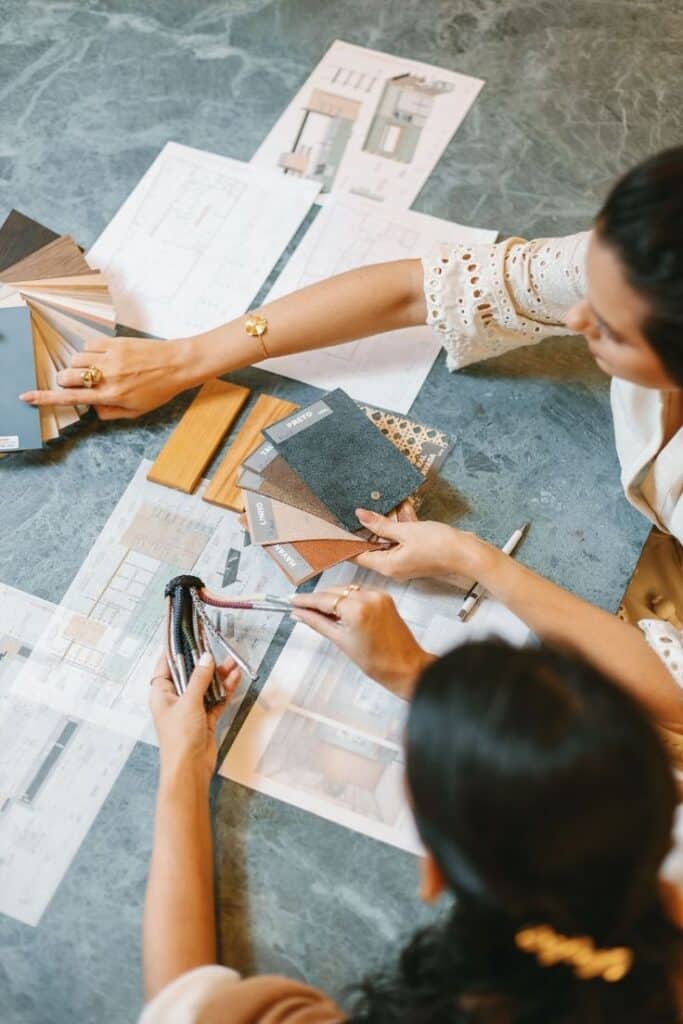 Interior designers selecting materials and colors for a project, with design plans in the background.