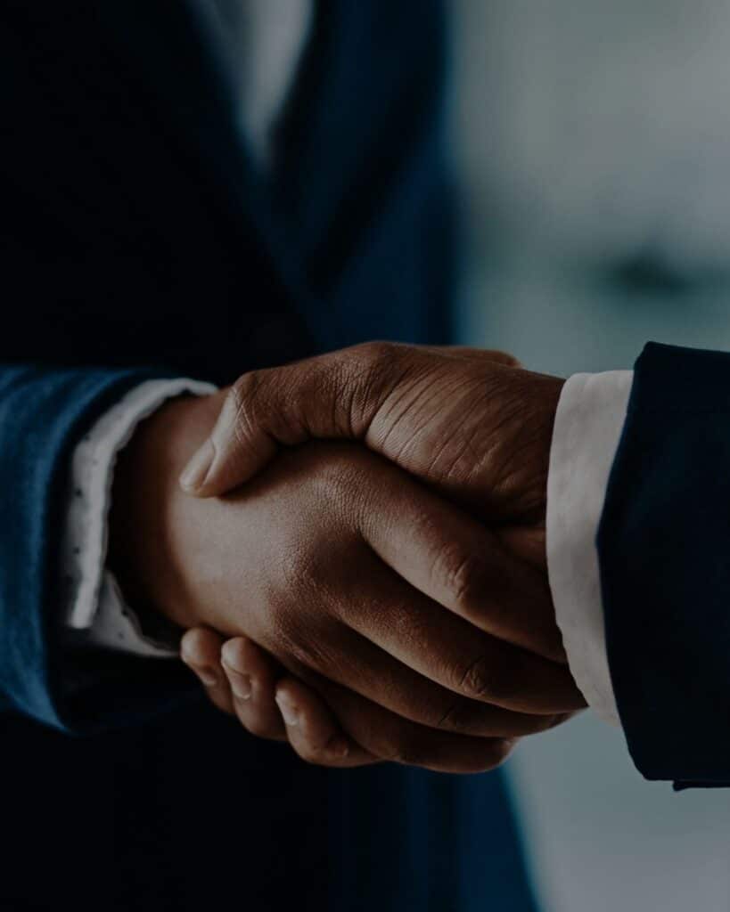 Handshake between business professionals in dark suits, symbolizing partnership and collaboration.