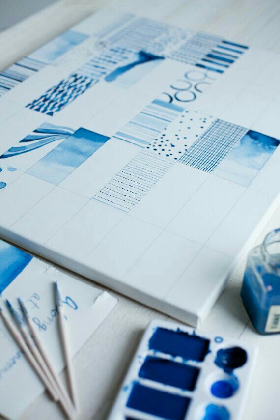 Blue watercolor patterns on a canvas with paint palette and brushes nearby. Artistic design and creativity concept.