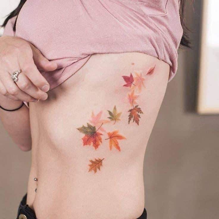 Autumn leaves tattoo on a person's side, showcasing a colorful and artistic design.