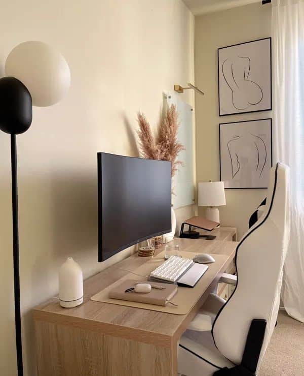 Minimalist home office with a wooden desk, curved monitor, ergonomic chair, decorative wall art, and natural lighting.