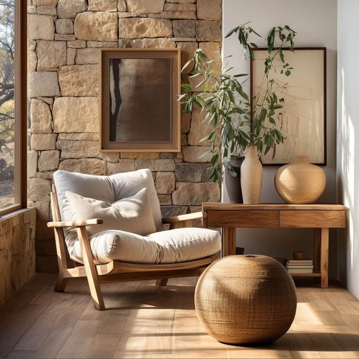 Cozy modern living room with armchair, stone wall, wooden table, and plants in natural light.