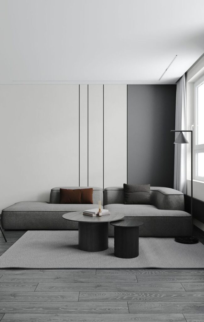 Minimalist living room with gray sectional sofa, modern coffee tables, and wood flooring.