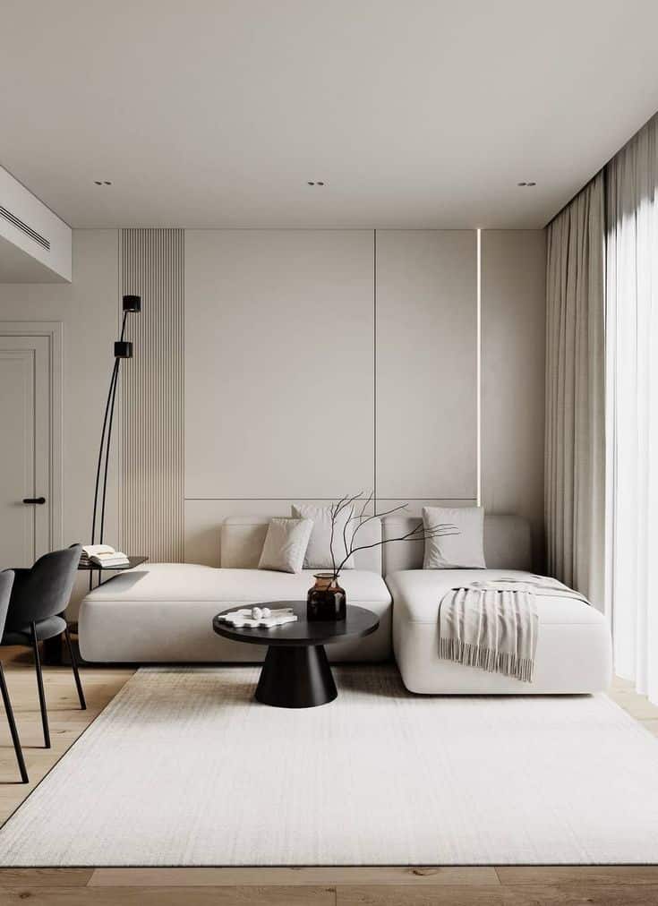 Modern living room with beige sectional sofa, black coffee table, and floor lamp in minimalist decor.