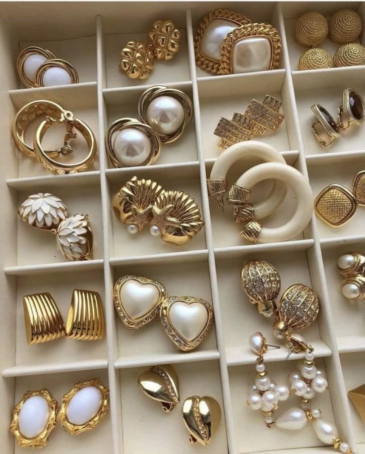 Assorted gold and pearl earrings displayed in an organized jewelry box, showcasing various elegant designs.