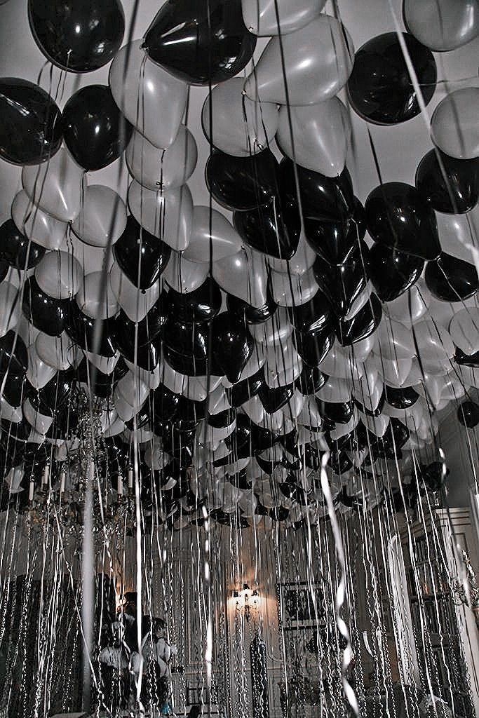 Black and white balloons with long strings hanging from the ceiling, creating a festive and elegant atmosphere.