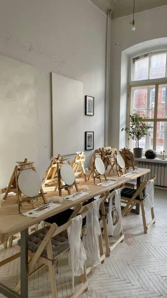 Art studio with easels and blank canvases ready for painting class in a sunlit room with wooden floors.