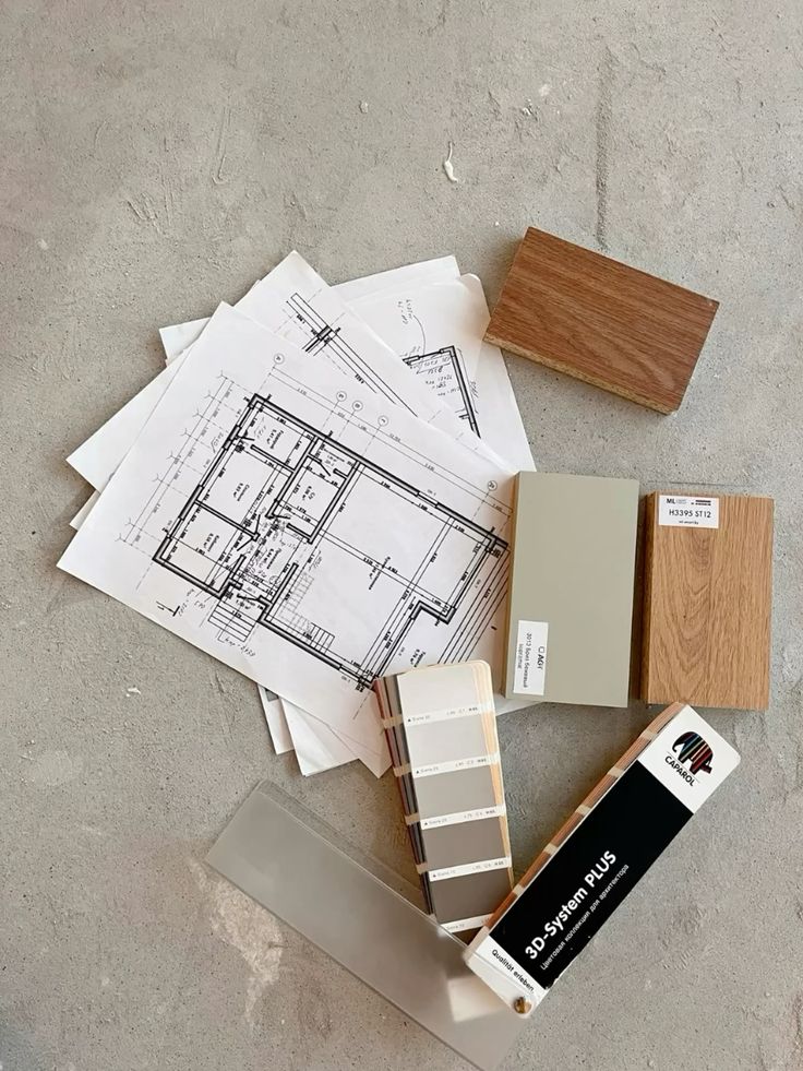 Architectural blueprints and color swatches on concrete floor, showcasing design planning and material selection.