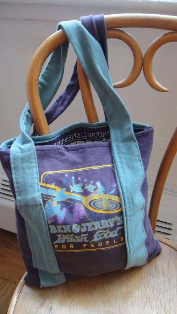 Colorful Ben & Jerry's tote bag on wooden chair, featuring artistic design and blue straps.