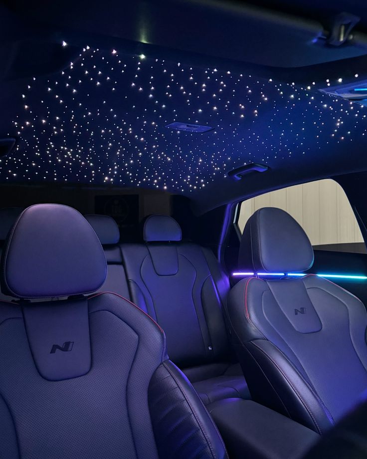 Car interior with starlit ceiling, ambient blue lighting, and luxury leather seats for an elegant driving experience.