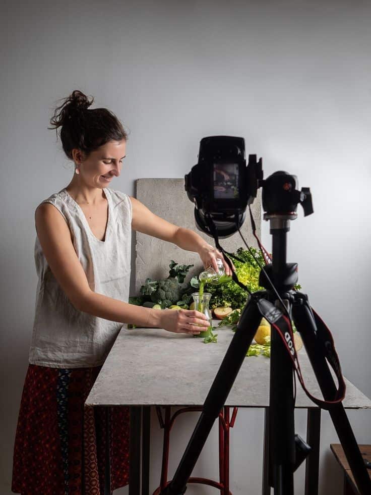 Woman preparing fresh smoothie with greens for a food Photography shoot.