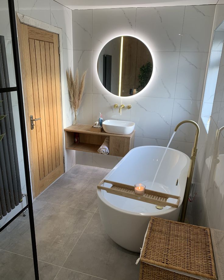 Modern bathroom with freestanding tub, round LED mirror, and wooden accents for a serene and stylish ambiance.
