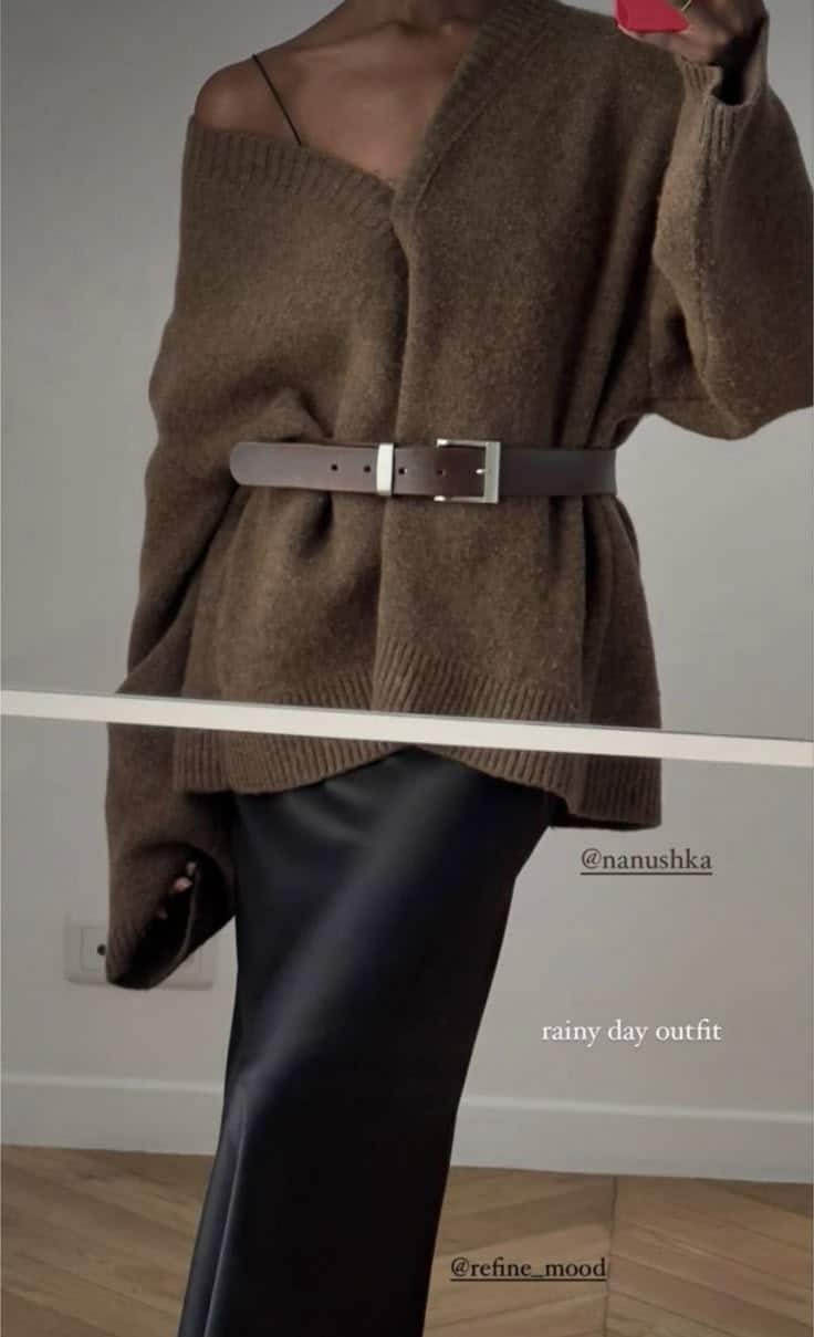 Woman in cozy brown sweater with a belt over dark skirt, perfect stylish rainy day outfit.