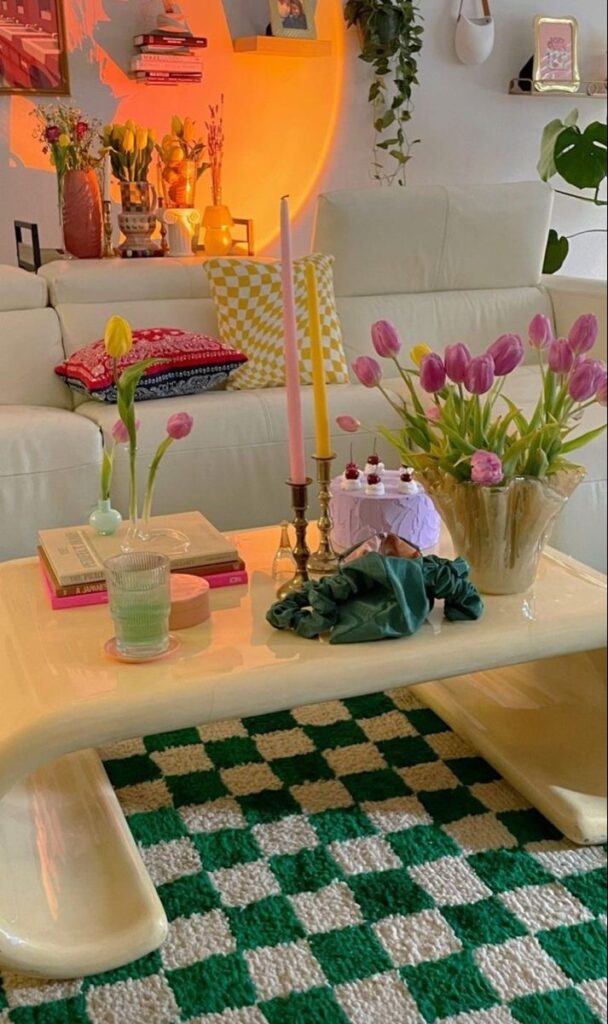 Stylish living room with tulips, candles, books, and cake on a modern coffee table, vibrant cozy decor.