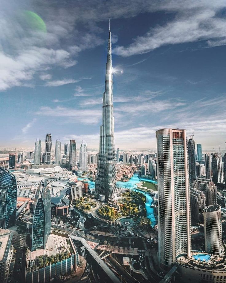 Aerial view of Dubai cityscape featuring the towering Burj Khalifa under a bright sky.